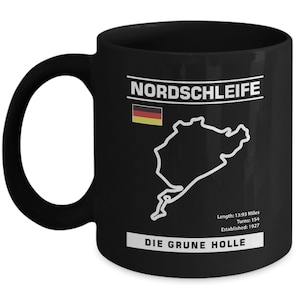 May include: Black ceramic mug with a white graphic of the Nordschleife race track, the German flag, and the text "Nordschleife Die Grune Hölle". The text below the track reads "Length: 13.93 Miles, Turns: 154, Established: 1927."