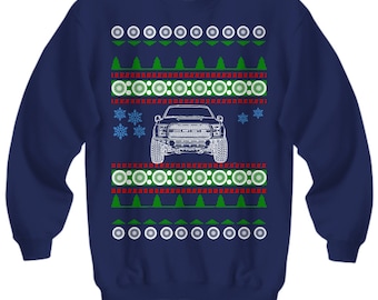 May include: Navy blue Christmas sweater with a white Ford F-150 truck design. The sweater features a repeating pattern of green trees, red and white snowflakes, and white circles.