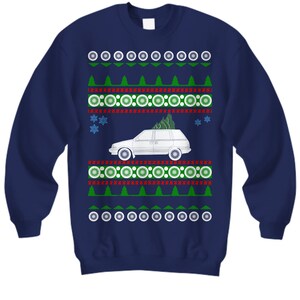 Puede incluir: Sudadera azul marino con un diseño navideño. El diseño presenta un coche familiar blanco con un árbol de Navidad encima, rodeado de árboles verdes, copos de nieve y patrones circulares en blanco, rojo y verde.