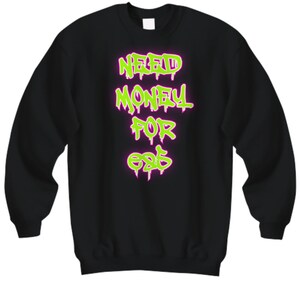 May include: Black sweatshirt with the neon green text "NEED MONEY FOR EATS" in a graffiti-style font. The text has a pink outline. The sweatshirt is a crew neck style.