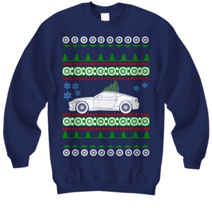 May include: A navy blue Christmas sweater with a white car and a Christmas tree on top. The sweater has a red and green pattern with snowflakes and circles.