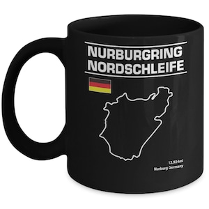 Puede incluir: Taza de café de cerámica negra con un contorno blanco de la pista de carreras de Nürburgring Nordschleife, la bandera alemana y el texto "Nurburgring Nordschleife" y "12.924mi Nurburg Germany".
