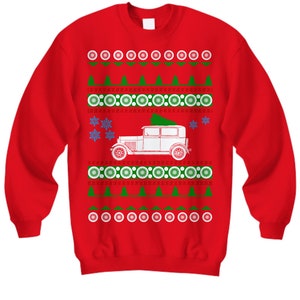 May include: Red Christmas sweater with a white vintage car carrying a green Christmas tree. The sweater has a repeating pattern of snowflakes, circles, and green triangles.