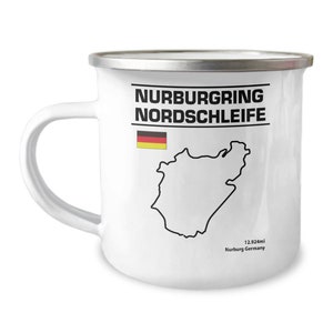 Puede incluir: Taza de esmalte blanco con un contorno negro de la pista de carreras de Nürburgring Nordschleife y el texto "Nurburgring Nordschleife" en negro. La bandera alemana está en la esquina superior izquierda. El texto "12.924mi Nurburg Germany" está en la parte inferior.