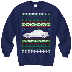 May include: A navy blue Christmas sweater with a white car and a green Christmas tree on the hood. The sweater has a red and white snowflake pattern.