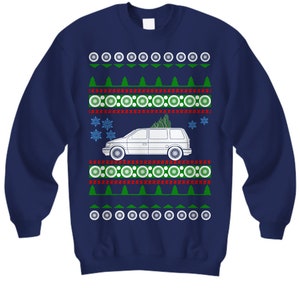 May include: A navy blue Christmas jumper featuring a white minivan carrying a Christmas tree. The jumper has a repeating pattern of red and white circles, green trees, and snowflakes.