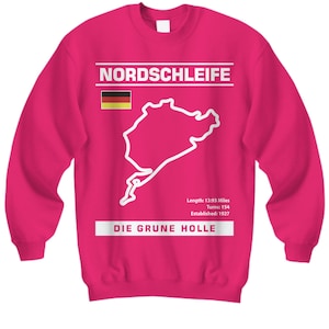 Op de afbeelding: Een magenta sweatshirt met de tekst "NORDSCHLEIFE" en een witte omtrek van een racecircuit. Daaronder staat de tekst "DIE GRUNE HOLLE". De Duitse vlag staat links. De tekst "Lengte: 22,42 km, Bochten: 154, Opgericht: 1927" is ook zichtbaar.