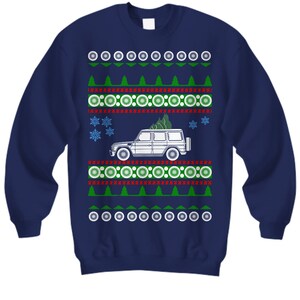 Könnte beinhalten: Ein marineblauer Weihnachtspullover mit einem weißen SUV, der einen Weihnachtsbaum transportiert. Der Pullover hat ein rotes und grünes Schneeflockenmuster.
