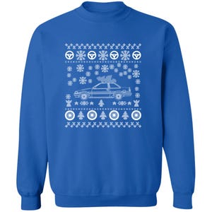May include: A royal blue sweatshirt with a white graphic design. The design features a car with a Christmas tree on top, surrounded by snowflakes, steering wheels, and Christmas trees. A festive holiday-themed apparel item.