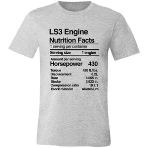 May include: A light gray t-shirt with the text "LS3 Engine Nutrition Facts" printed in black. The graphic includes engine specifications such as horsepower, torque, displacement, and bore measurements in inches.