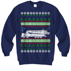 May include: A navy blue Christmas sweater with a white outline of a concrete pump truck and a green Christmas tree. The sweater has a red and white snowflake pattern and a green and white Christmas tree pattern.