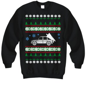 May include: Black Christmas sweater with a white silhouette of a car carrying a Christmas tree. The sweater has a red, white, and green pattern with snowflakes and tire tracks.
