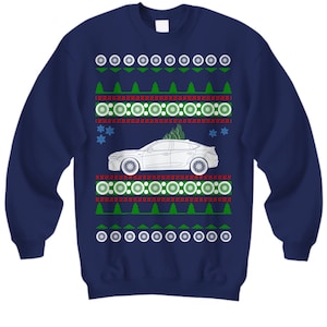 May include: A navy blue Christmas sweater with a white car and a green Christmas tree on a red and white patterned background.