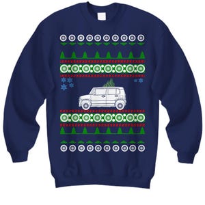 May include: Navy blue sweatshirt with a festive design. The design includes a white SUV with a Christmas tree on top, surrounded by green trees, red lines, white circles, and snowflakes. A fun, holiday-themed sweater.