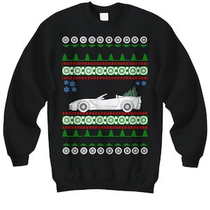 May include: Black sweatshirt with a festive design. The design features a white convertible car with a Christmas tree in the back, surrounded by green trees, snowflakes, and red and white circular patterns. A fun holiday sweater.