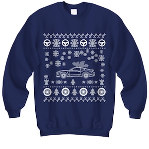 May include: A navy blue Christmas sweater with a white snowflake pattern and a white outline of a car with a Christmas tree on top.