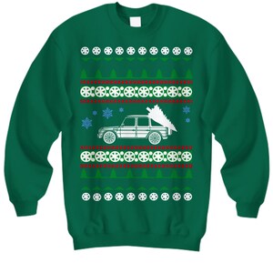 May include: Green Christmas sweater with a white car carrying a Christmas tree. The sweater has a repeating pattern of snowflakes, trees, and circles.