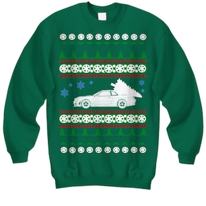 Könnte beinhalten: Grüner Weihnachtspullover mit einem weißen Auto, das einen Weihnachtsbaum transportiert. Der Pullover hat ein sich wiederholendes Muster aus Schneeflocken, Weihnachtsbäumen und Reifenspuren.