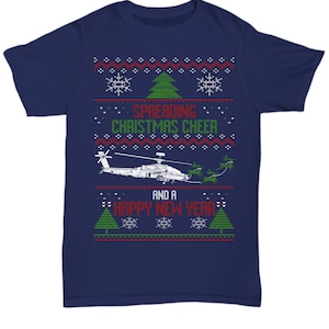 May include: Navy blue t-shirt with a Christmas-themed design featuring a helicopter, snowflakes, and Christmas trees. The text "Spreading Christmas Cheer and a Happy New Year" is printed on the shirt.