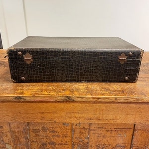 May include: A vintage brown leather suitcase with a crocodile embossed pattern and brass hardware.