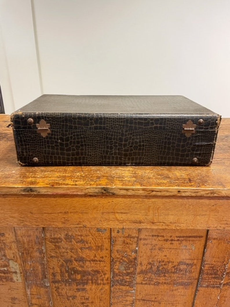 May include: A vintage brown leather suitcase with a crocodile embossed pattern and brass hardware.