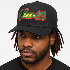 May include: Black baseball cap with the embroidered text "Free-ish" in green, red, and yellow. The cap has a curved brim and a small gold emblem on the side. A stylish accessory for casual wear.
