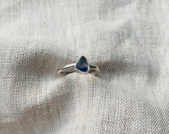 May include: A silver ring with a teardrop-shaped blue gemstone.