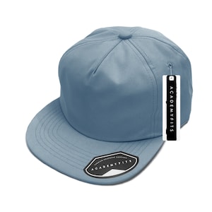 May include: A light blue, flat-brimmed baseball cap with a structured crown. The cap has a matching brim and a small tag with the text "ACADEMY FITS". The cap is made by the "PREMIUM HEADWEAR COMPANY".