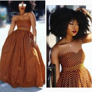 May include: A strapless maxi dress with a yellow and orange geometric print. The dress has a fitted bodice and a flowing skirt.