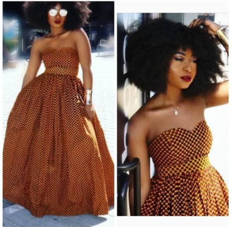 May include: A strapless maxi dress with a yellow and orange geometric print. The dress has a fitted bodice and a flowing skirt.