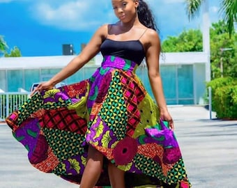May include: A woman wearing a black tank top and a colorful high-low skirt with a geometric pattern. The skirt is made of a fabric with a bright, bold print. She is wearing black high heels.