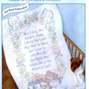 May include: A white crib quilt top with a floral border and a verse of the prayer "Now I Lay Me Down to Sleep." The quilt is 40 inches by 60 inches and is made of cotton and poly broadcloth.