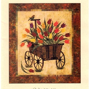 May include: A quilt featuring a spring wagon filled with colorful tulips. The wagon has large spoked wheels and is topped with a small bird. The quilt measures 30" x 34". The text "Spring Wagon" and "Laundry Basket Quilts" are also visible.