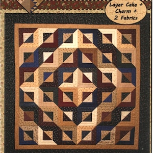 May include: A quilt pattern titled "KT Barn Raising" featuring a geometric design in shades of tan, brown, navy, and burgundy. The pattern includes the text "Layer Cake + Charm + 2 Fabrics" and is designed by Lynne Hagmeier.