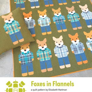 May include: A quilt and pillow featuring a repeating pattern of fox figures. Each fox is dressed in a flannel shirt and jeans. The quilt and pillow have a green background with an orange border. The text "Foxes in Flannels" is visible.