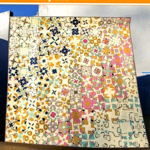 May include: A colorful quilt with a geometric pattern in shades of cream, blue, pink, yellow, and black. The quilt is 68 inches by 68 inches and features the text "Only One" and "Orange dot Quilts".