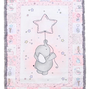 May include: A pink and white baby blanket with a gray elephant holding a pink star balloon. The blanket has a gray fuzzy border and a patchwork design with stars, moons, and elephants.
