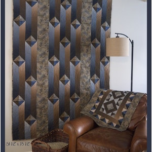 May include: A large quilt with a geometric design in shades of brown, blue, and gray hangs on a wall. The quilt measures 54.5 x 78.5 inches. A matching pillow rests on a brown leather armchair. The text "Gentlemen's Agreement" is at the top.