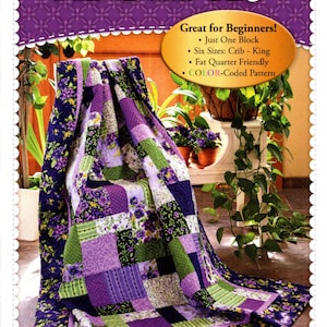 May include: A purple and green quilt with a floral pattern. The quilt is folded and sitting on a chair in a garden setting. The text "Easy as ABC and 123" is at the top of the image. The text "Great for Beginners!" is below the quilt. The text "Just One Block", "Six Sizes: Crib - King", "Fat Quarter Friendly", and "COLOR-Coded Pattern" are listed below the text "Great for Beginners!" The text "Shabby Fabrics.com" is at the bottom of the image.
