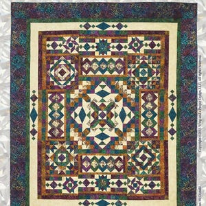 May include: A rectangular quilt titled GEMSTONE by Wing and a Prayer Design, featuring a complex geometric pattern with diamond and star motifs in shades of purple, teal, green, and cream. The border is a dark, mottled fabric with text.