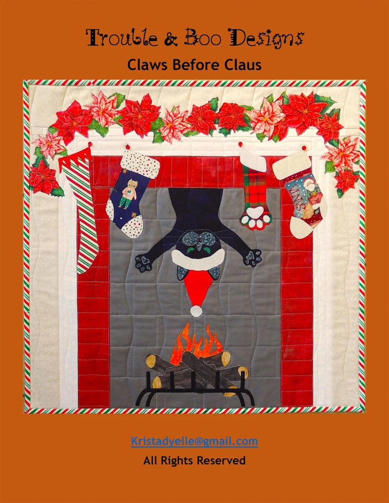 K&ouml;nnte beinhalten: Eine weihnachtliche Steppdecke mit einer schwarzen Katze in einem Kamin. Sie zeigt Str&uuml;mpfe, Weihnachtssternblumen und den Text "Claws Before Claus". Die Steppdecke ist mit einem rot-gr&uuml;n gestreiften Rand versehen.