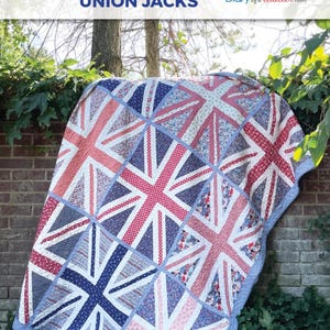 May include: A quilt featuring a repeating Union Jack pattern composed of various red, white, and blue floral and geometric fabric prints. The quilt has a light blue border and is labeled as a Super Sized Regent Street Union Jacks pattern.