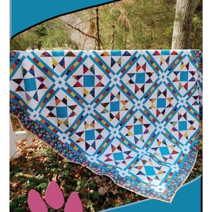 May include: A handmade quilt with a geometric star pattern in shades of blue, orange, purple, and yellow on a white background. The quilt measures 71" x 86" and is designed by Deb Heatherly. The quilt is titled "Crossroads".