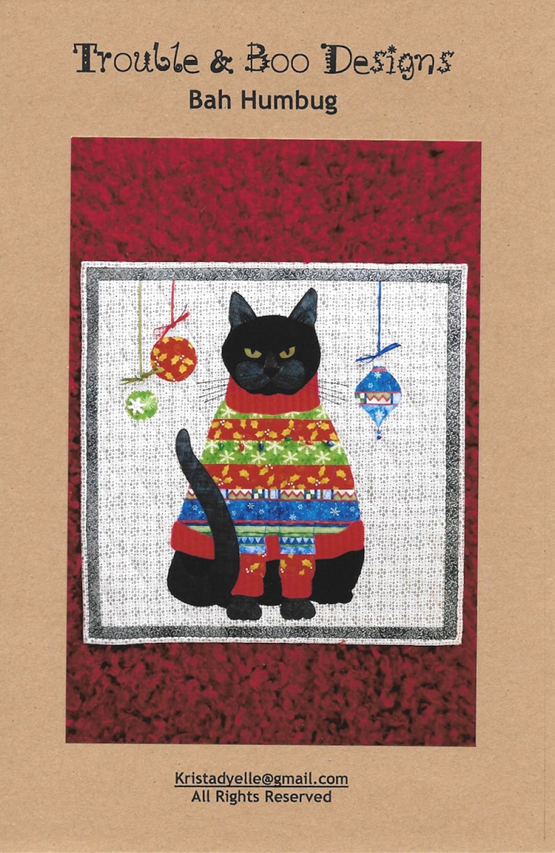 May include: A black cat wearing a colorful Christmas sweater with a red, green, blue, and white pattern. The cat is sitting on a white background with red ornaments hanging from the top. The text "Bah Humbug" is written above the cat. The text "Kristadyelle@gmail.com" and "All Rights Reserved" is written below the cat.