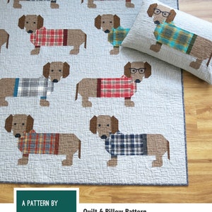May include: A quilt pattern featuring a patchwork design of dogs wearing sweaters. The pattern includes instructions for making two quilt sizes and a pillow cover. The text "Dogs in Sweaters" is at the top of the image. The text "A Pattern by Elizabeth Hartman" is at the bottom of the image. The text "Quilt & Pillow Pattern" is in the center of the image.