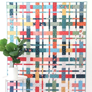 May include: A quilt pattern called "Plaidy Cake" by Cluck Cluck Sew. The quilt is a layer cake or fat quarter quilt in 5 sizes. The quilt is made with a variety of colorful fabrics in a plaid pattern.
