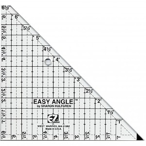 May include: A clear, triangular quilting ruler with black grid lines and inch measurements. The ruler has the text "EASY ANGLE" and "by SHARON HULTGREN". It also includes a small hole for easy handling. Made in the U.S.A.