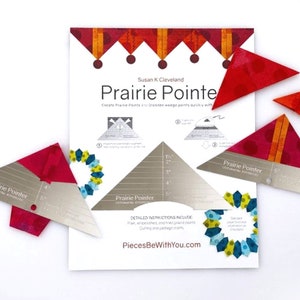 May include: A set of two silver quilting rulers with the text "Prairie Pointer" printed on them. The rulers are on a white background with a printed instruction sheet for creating prairie points and dresden wedges. The instruction sheet has a red, orange, and yellow design at the top.