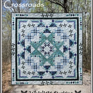 May include: A quilt pattern called "Crossroads" by "Whirligig Designs". The quilt is made with a variety of blue, green, and white fabrics. The quilt is displayed in front of a forest background.