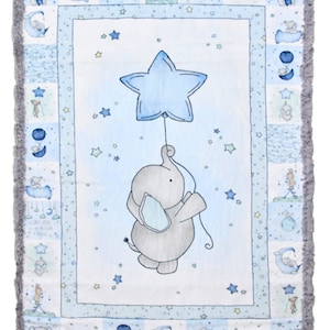 May include: A blue and white baby blanket with a gray elephant holding a blue star balloon. The blanket has a gray, fuzzy border and a patchwork design with stars, moons, and elephants.